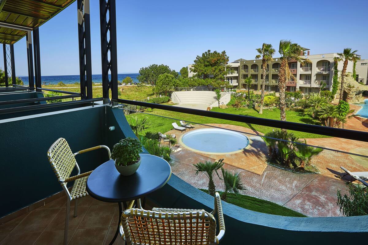Un balcon donnant sur une piscine, des palmiers et un immeuble doté de nombreux balcons.