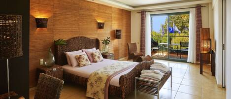 A spacious bedroom with a large bed, wicker furniture, and a view of the outdoors through a sliding glass door.