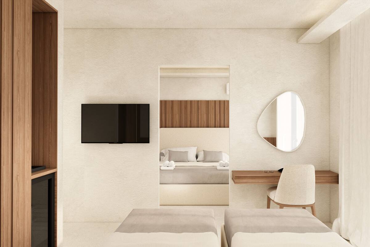 Une chambre moderne avec un téléviseur fixé au mur, une tête de lit en bois, une table de chevet, une chaise et un grand miroir.