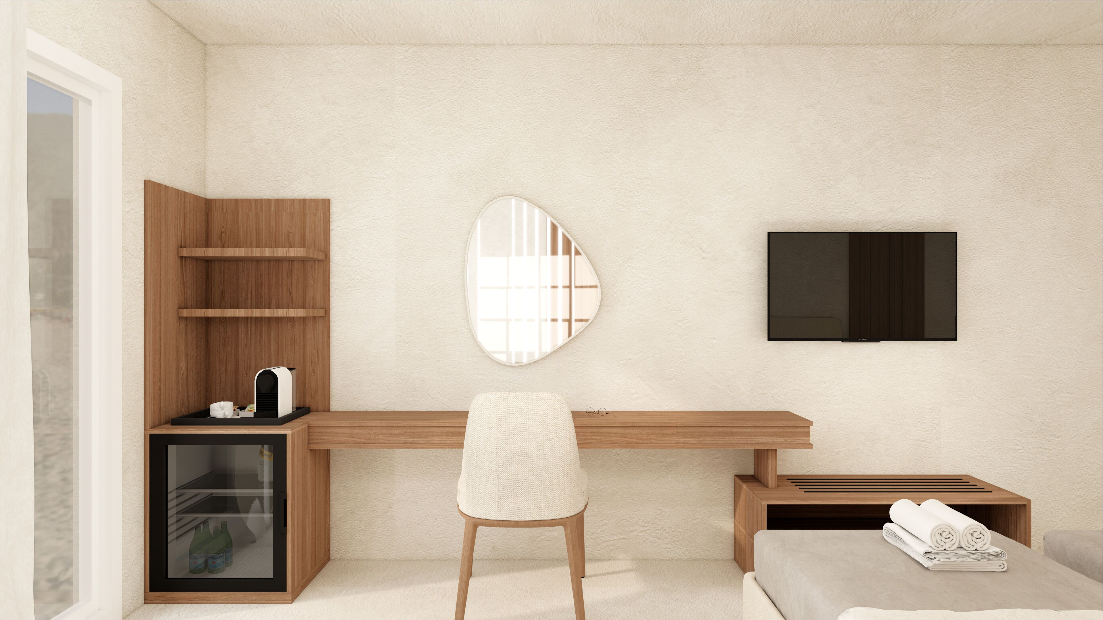 A modern hotel room with a wooden desk, a comfortable chair, a built-in minibar, a large mirror, and a flat-screen TV.