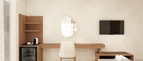A modern hotel room with a wooden desk, a comfortable chair, a built-in minibar, a large mirror, and a flat-screen TV.