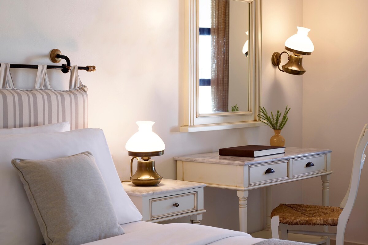 Une chambre bien rangée, avec un lit, des tables de chevet, une commode, une chaise et un miroir.