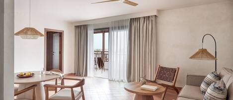 Un salón amplio con una mesa de comedor, sillas, un sofá, un ventilador de techo y vistas a través de un ventanal.