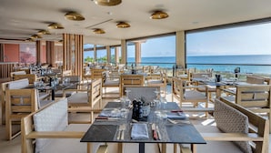 A restaurant with outdoor seating overlooking the sea, featuring wooden furniture and modern lighting. - Creta Maris Resort - All Inclusive (Hersonissos)