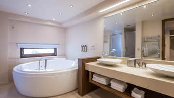 A modern bathroom with a large bathtub, two sinks, a mirror, and a towel rack.