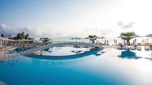 A clear blue pool with a bridge, sun loungers, umbrellas, and a view of the sea. - Creta Maris Resort - All Inclusive (Hersonissos)