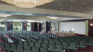 A conference room with rows of chairs, a projector screen, and a table with a tablecloth.