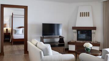 A hotel room with a four-poster bed, a flat-screen TV, a fireplace, and two sofas.