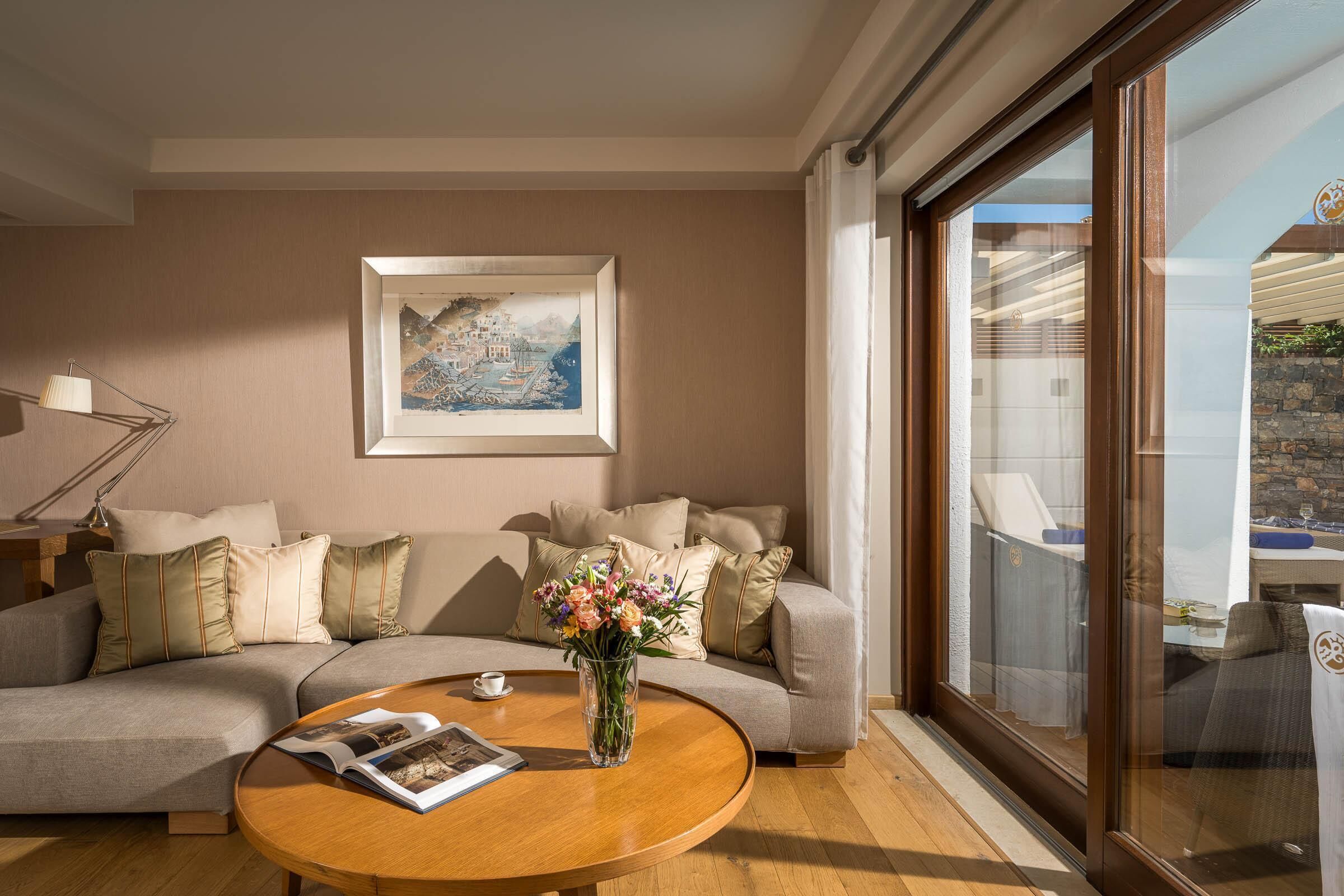 Una sala de estar moderna con un sofá, una mesa de centro con una revista, un jarrón con flores y un cuadro en la pared.