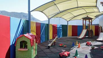 Un área de juegos infantiles con tobogán, estructura para escalar y diversos juguetes.