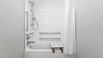 A white bathroom with a bathtub, a shower, and a small wooden stool.