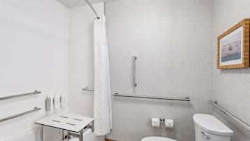 Un baño moderno con ducha, inodoro y una mesita con artículos de aseo.