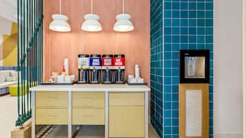 Un área de cocina moderna con una encimera, tres lámparas colgantes y una estación de café en la pared con recipientes etiquetados.