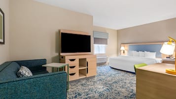 A hotel room with a bed, a desk, a TV, a chair, and a small table.