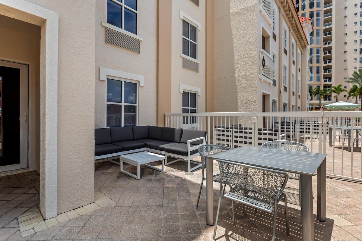 Un patio con mobiliario exterior, incluyendo un sofá y una mesa con sillas.