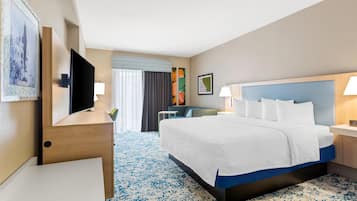 A hotel room with a bed, bedside table, TV, and a desk with a chair.