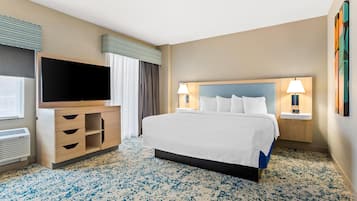 A hotel room with a large bed, a TV, a desk, and a lamp.