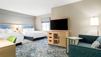 Una habitación de hotel con cama, escritorio, silla, televisor y una mesita.