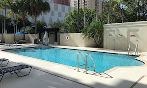 A swimming pool with a lifeguard chair, lounge chairs, and a covered seating area.