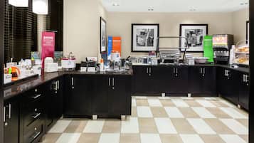 A modern kitchen with black cabinets, a checkered floor, and various appliances like a coffee maker and toaster.