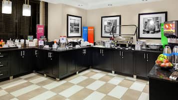 A modern kitchen with black cabinets, a checkered floor, and various appliances.