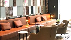 A modern lounge area with a long sofa, two armchairs, and a small table with a lamp. - Mercure Hotel Kaiserhof Frankfurt City Center (Frankfurt)