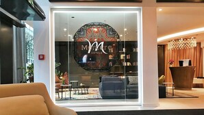 A hotel lobby with a large, circular logo on the glass wall, a reception desk, and a seating area with a sofa and tables. - Mercure Hotel Kaiserhof Frankfurt City Center (Frankfurt)