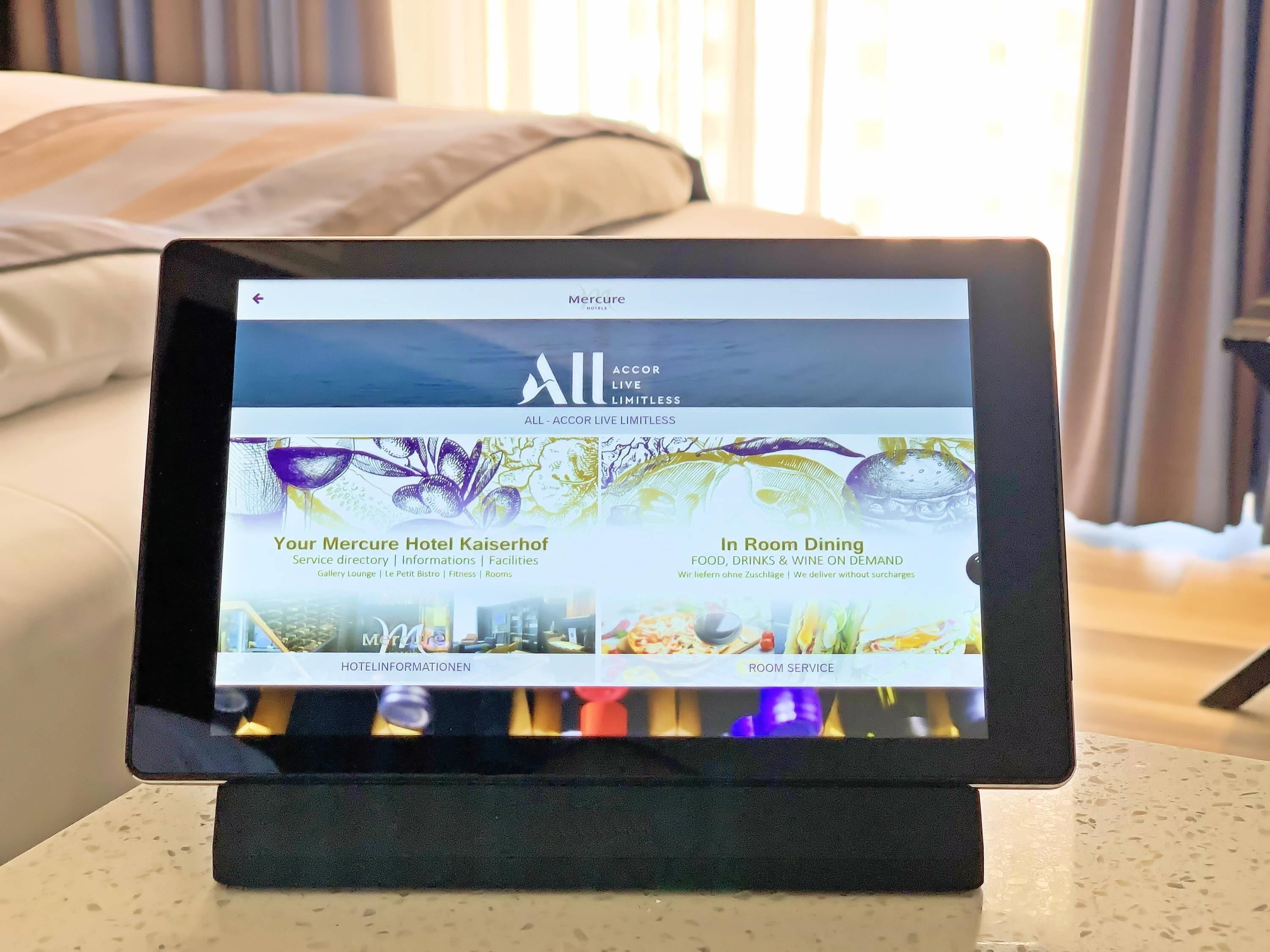 Ein Tablet zeigt Hotelinformationen mit Bereichen für Dienstleistungen, Zimmerservice und Annehmlichkeiten.