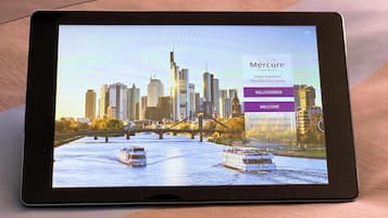 Una tableta muestra un sitio web de hotel con un fondo de horizonte urbano, destacando el Hotel Kaiserhof en el centro de Frankfurt.
