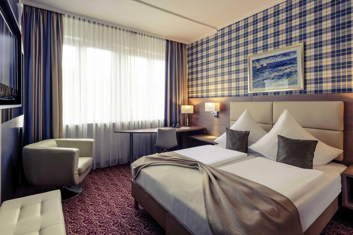 Une chambre d’hôtel équipée d’un lit, d’un bureau, d’une chaise et d’un téléviseur.