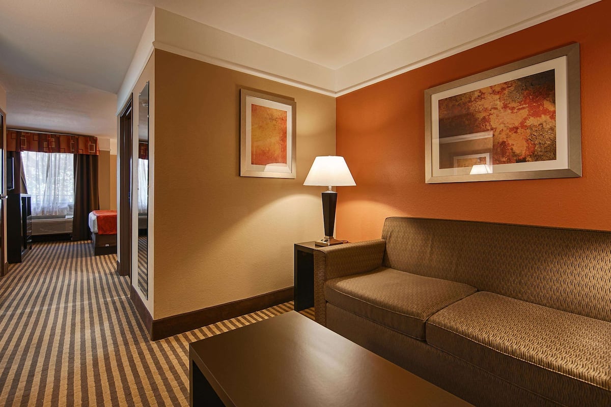Ett hotellrum med en soffa, ett bord, en lampa och två inramade tavlor på väggen.