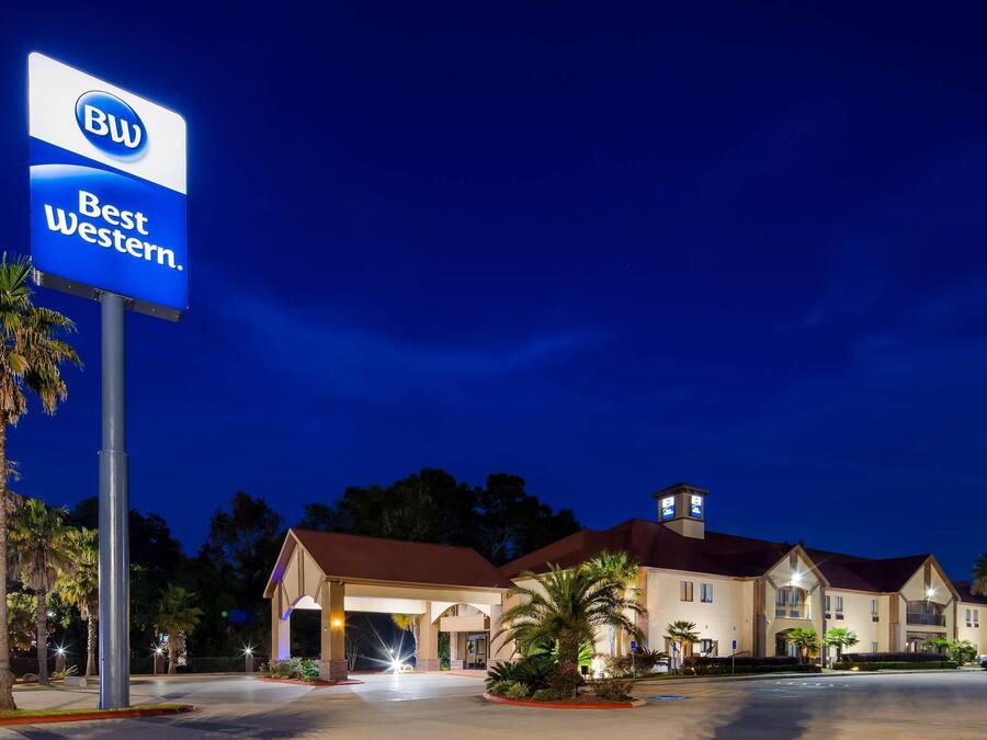Ein Best Western Hotel bei Nacht mit einer gut sichtbaren Beschilderung, einem Parkplatz und einem Gebäude mit rotem Dach.