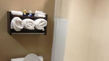 A bathroom with a toilet, a shelf with towels, and a bathtub.