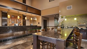 A hotel lobby with a reception desk, seating area, and a decorative wall. - Best Western Inn & Suites - Lake Charles (Lake Charles)
