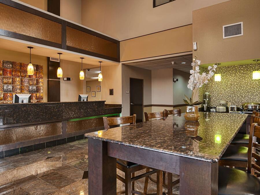 Een hotellobby met een receptiebalie, een zithoek en een decoratieve muur.