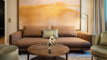 Un salon moderne avec un canapé marron, une table basse ronde ornée d’un vase de fleurs et un grand tableau abstrait accroché au mur.