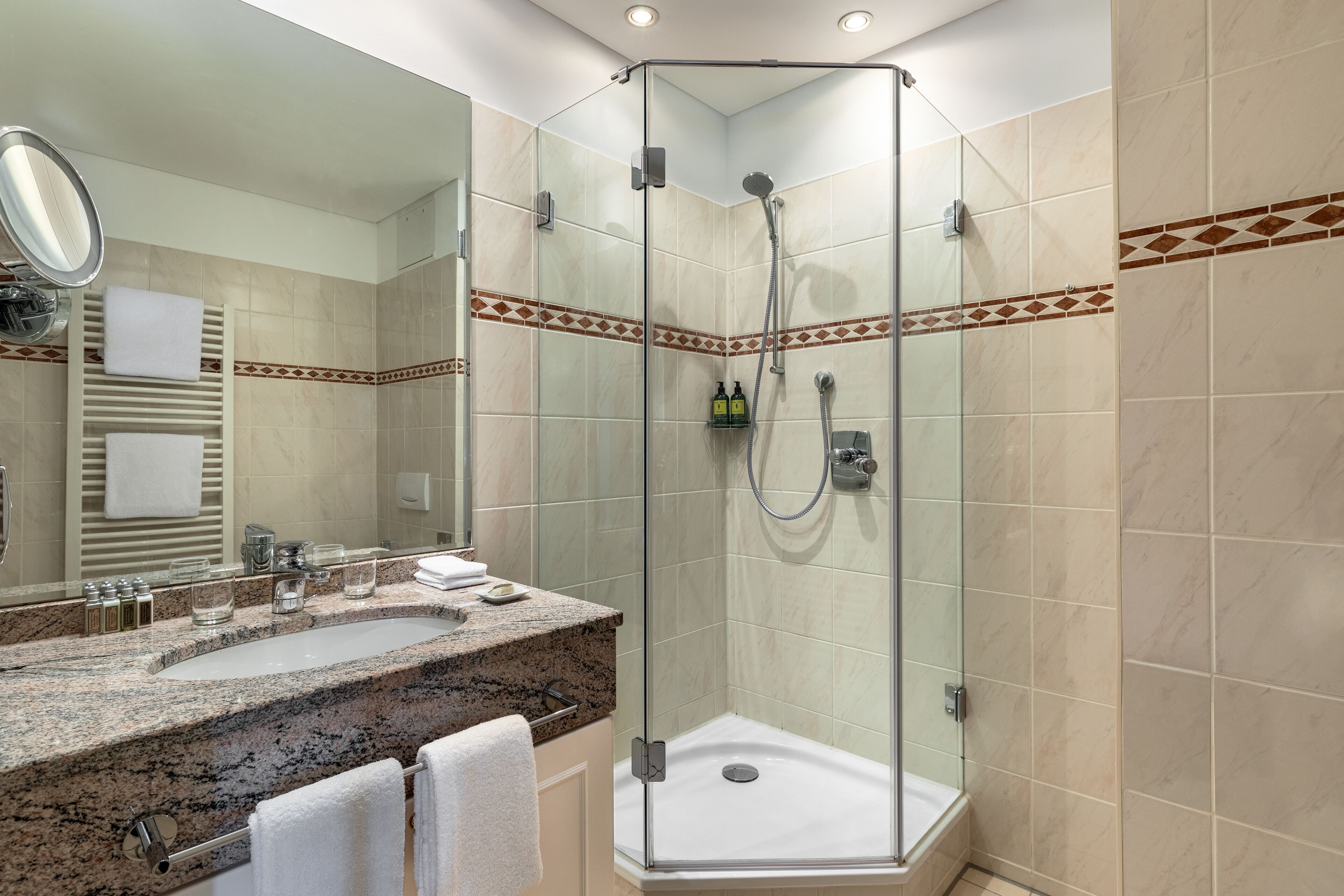 A modern bathroom with a glass-enclosed shower, dual sinks, and a large mirror.