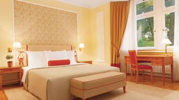 A hotel room with a large bed, a desk, and a chair.