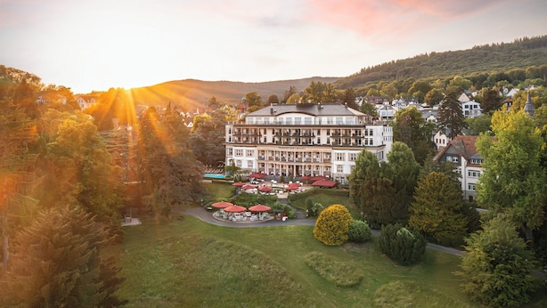 A large hotel with a central courtyard, multiple dining areas, and a view of surrounding hills.