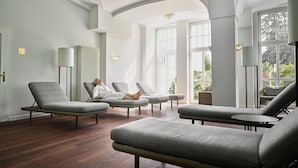 A spacious room with modern furniture, large windows, and a high ceiling.
