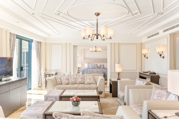 Amplia habitación de hotel con una cama grande, un sofá, un televisor y un comedor.