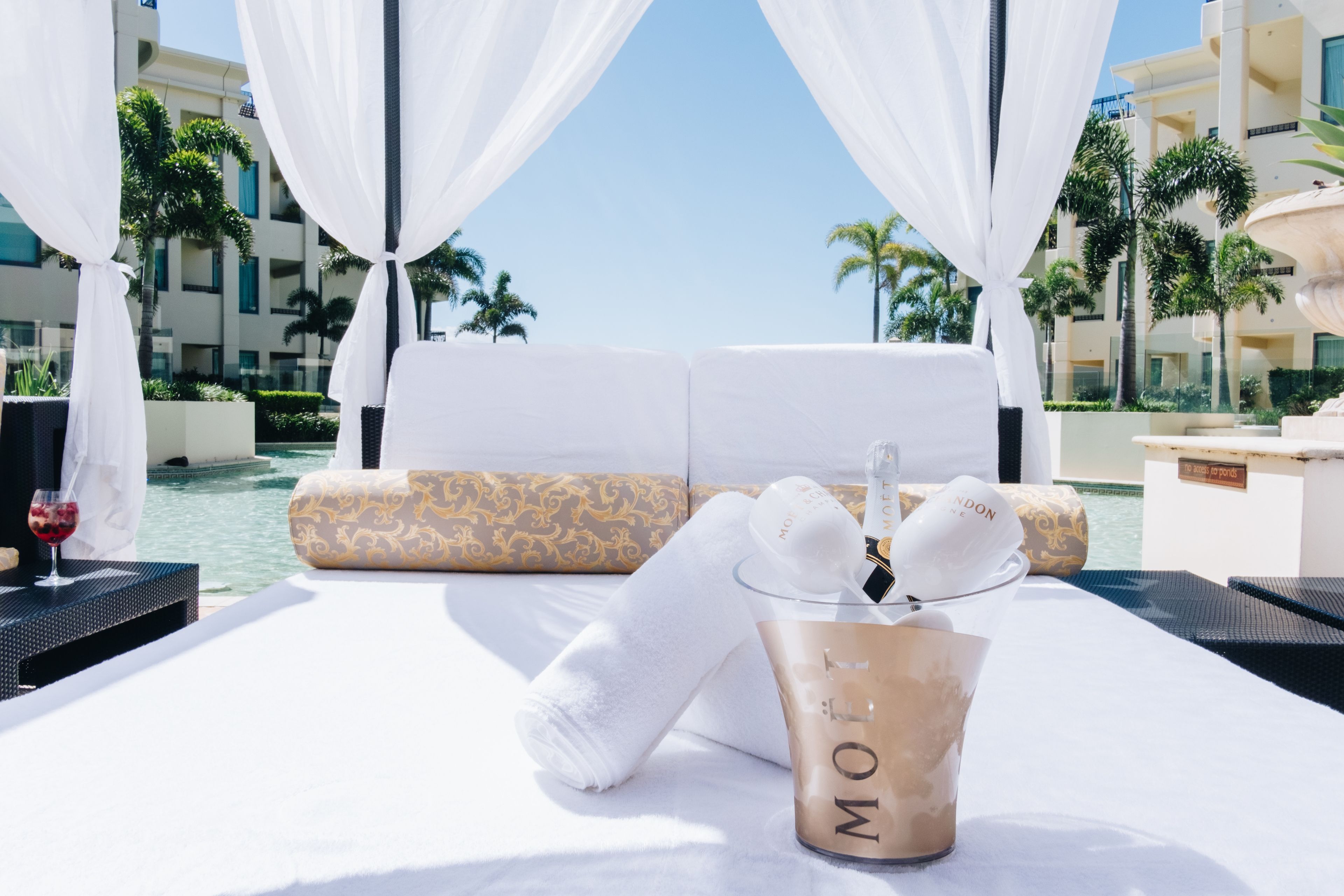 Una habitación lujosa con cama, minibar y vistas a la piscina y palmeras.