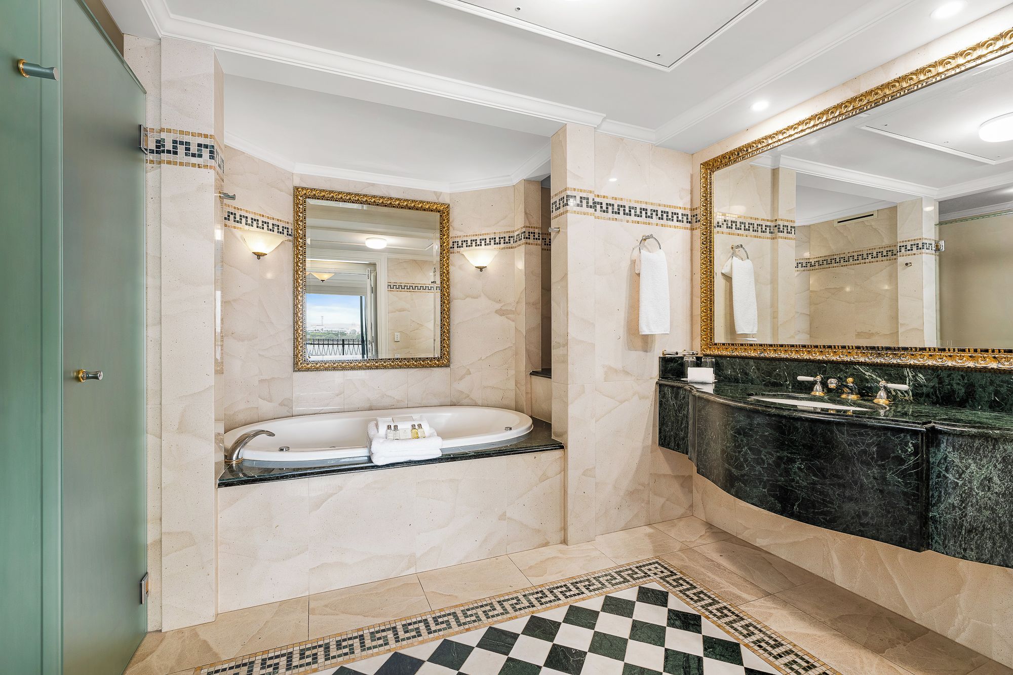 A modern bathroom with a freestanding bathtub, a vanity with a dark marble countertop, and a large mirror with a gold frame.