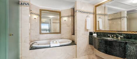 A modern bathroom with a freestanding bathtub, a vanity with a dark marble countertop, and a large mirror with a gold frame.