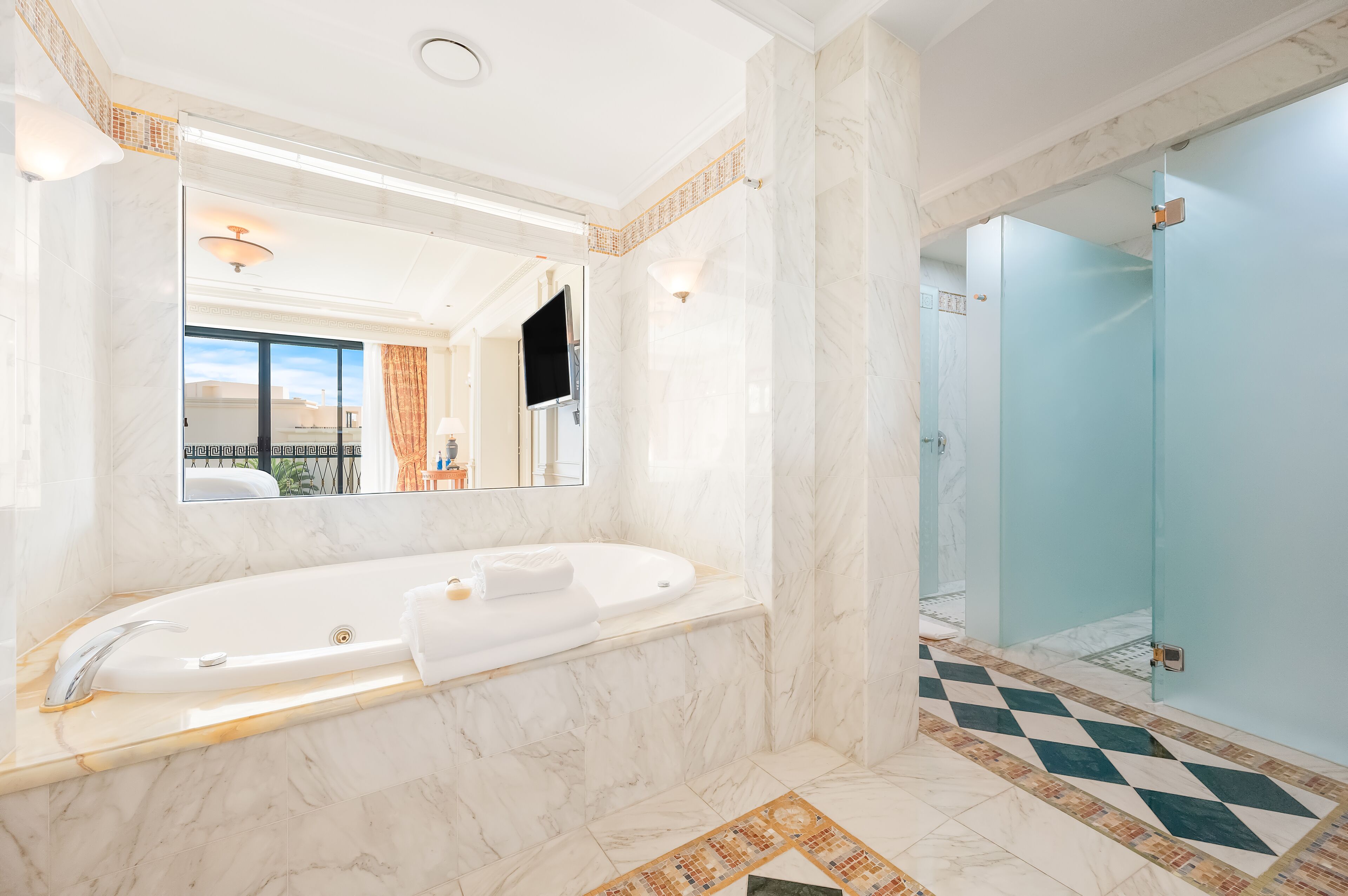 A modern bathroom with a large bathtub, a glass shower enclosure, and a tiled floor.