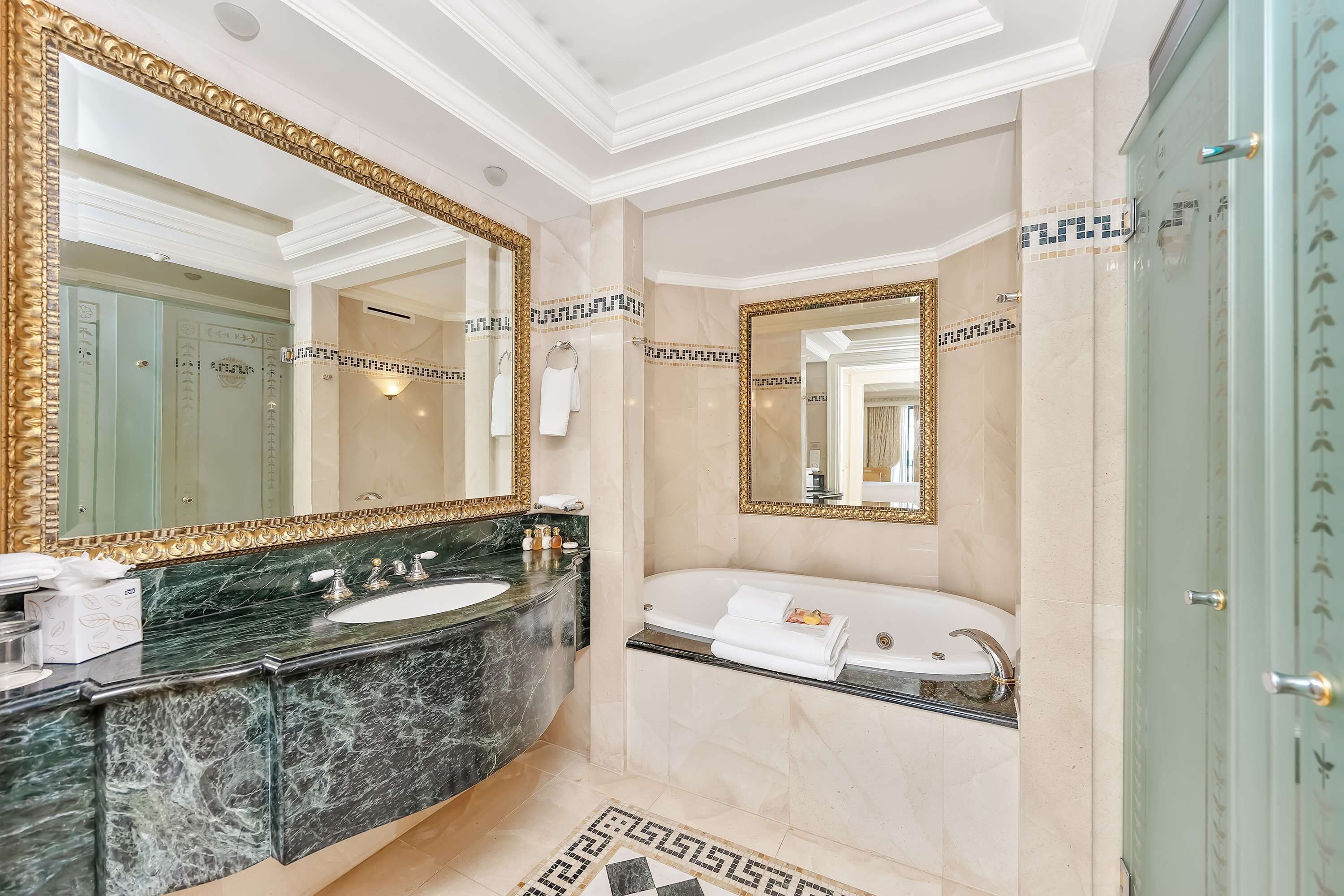 A luxurious bathroom with a double sink vanity, a bathtub, and a large mirror with an ornate frame.