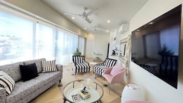 Una sala de estar moderna con un sofá, sillones, una mesa de centro y un televisor montado en la pared.
