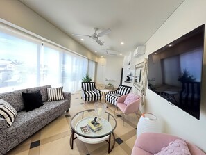 Una sala de estar moderna con un sofá, sillones, una mesa de centro y un televisor montado en la pared.