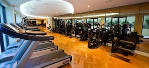 Un gimnasio con cintas de correr, máquinas de pesas y equipo de ejercicio.