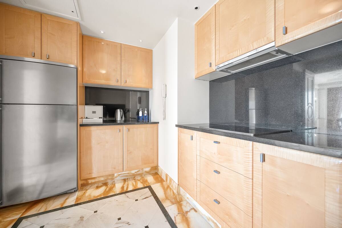 A modern kitchen with wooden cabinets, stainless steel appliances, and a black countertop.